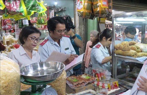 Officers of HCM City's food safety management board inspect invoices of a store in a traditional market in District 4. (Photo: VNA)