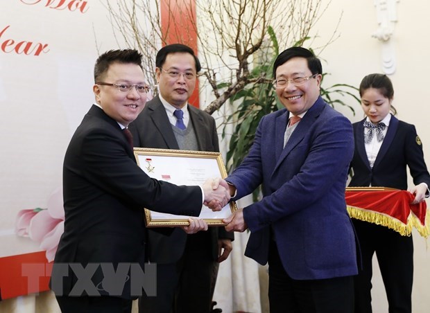 Deputy Prime Minister and Foreign Minister Pham Binh Minh (right) presents the insignia “For the cause of the diplomatic sector” to Deputy General Director of the Vietnam News Agency Le Quoc Minh (Photo: VNA)