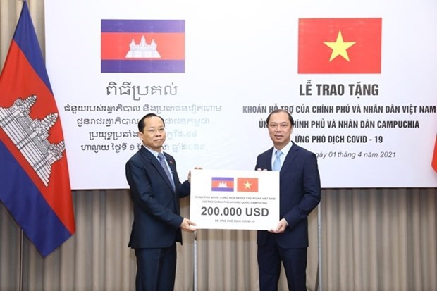 Vietnam hands over 200,000 USD to help Cambodia fight COVID-19 Vietnamese Deputy Minister of Foreign Affairs Nguyen Quoc Dung (R) presents the token of the aid worth 200,000 USD to Cambodian Ambassador to Vietnam Chay Navuth. (Photo: VNA)