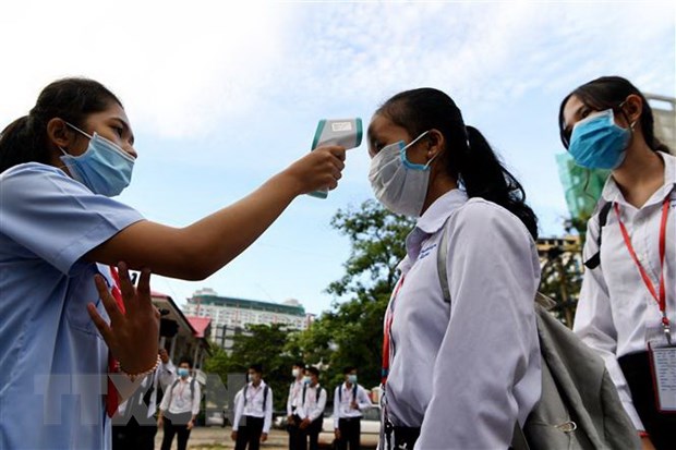 Học sinh được kiểm tra thân nhiệt trước khi vào lớp nhằm ngăn sự lây lan của dịch COVID-19 tại thủ đô Phnom Penh, Campuchia. (Ảnh: AFP/TTXVN)