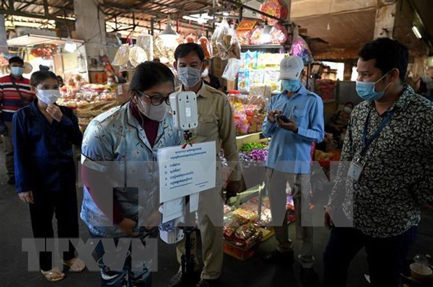 COVID-19 continues spreading in Cambodia, reducing in Laos Checking people's body temperature at a market in Phnom Penh (Photo: AFP/VNA)