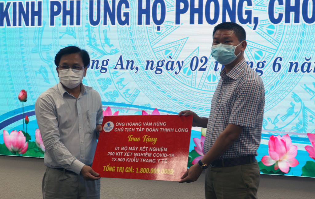 Chairman of Thinh Long Group - Hoang Van Hung (R) presents a symbolic board to support 1.8 billion VND