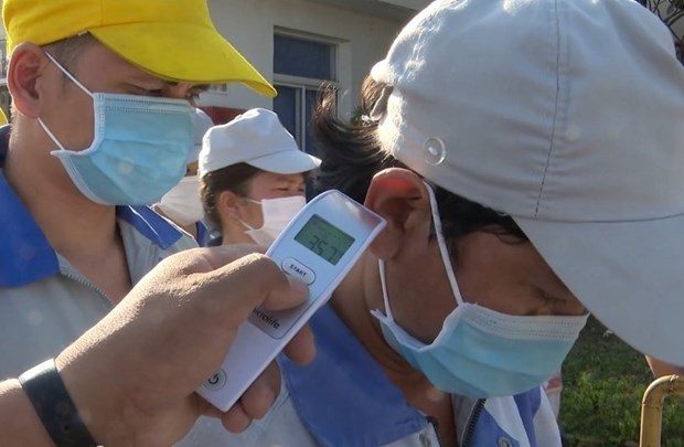 Labour Confederation proposes health insurance premium exemption Taking body temperature of workers (Photo: VNA)
