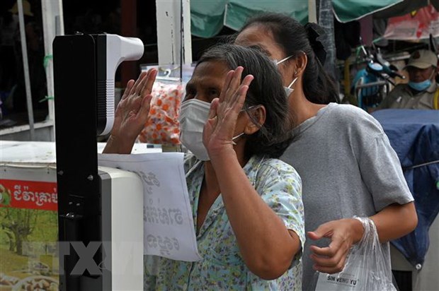 Đo thân nhiệt nhằm ngăn ngừa sự lây lan của dịch COVID-19 trước khi vào chợ tại Phnom Penh, Campuchia. (Ảnh: AFP/TTXVN)