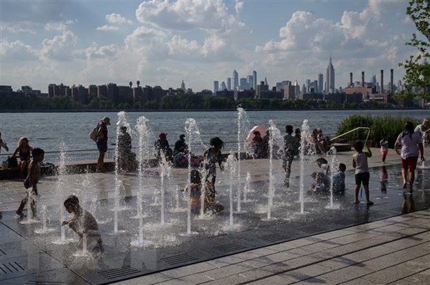 Trẻ em giải nhiệt trong thời tiết nắng nóng tại đài nước tại Mỹ. (Ảnh: AFP/TTXVN)