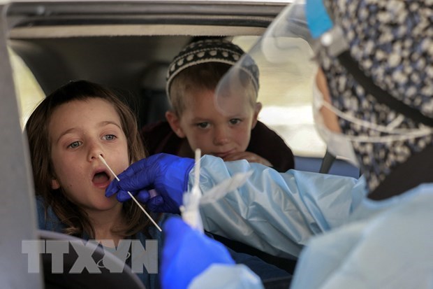 Nhân viên y tế lấy mẫu xét nghiệm COVID-19 cho một em nhỏ. (Ảnh: AFP/TTXVN)