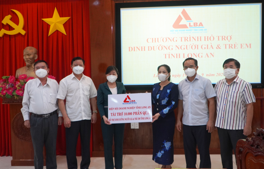 Long An Business Association supports 10,000 gifts for the elderly and children Standing Vice Chairwomam of the Provincial Business Association - Ninh Thi Bich Thuy (3rd, R) presents a symbolic board to support 10,000 gifts to Long An province