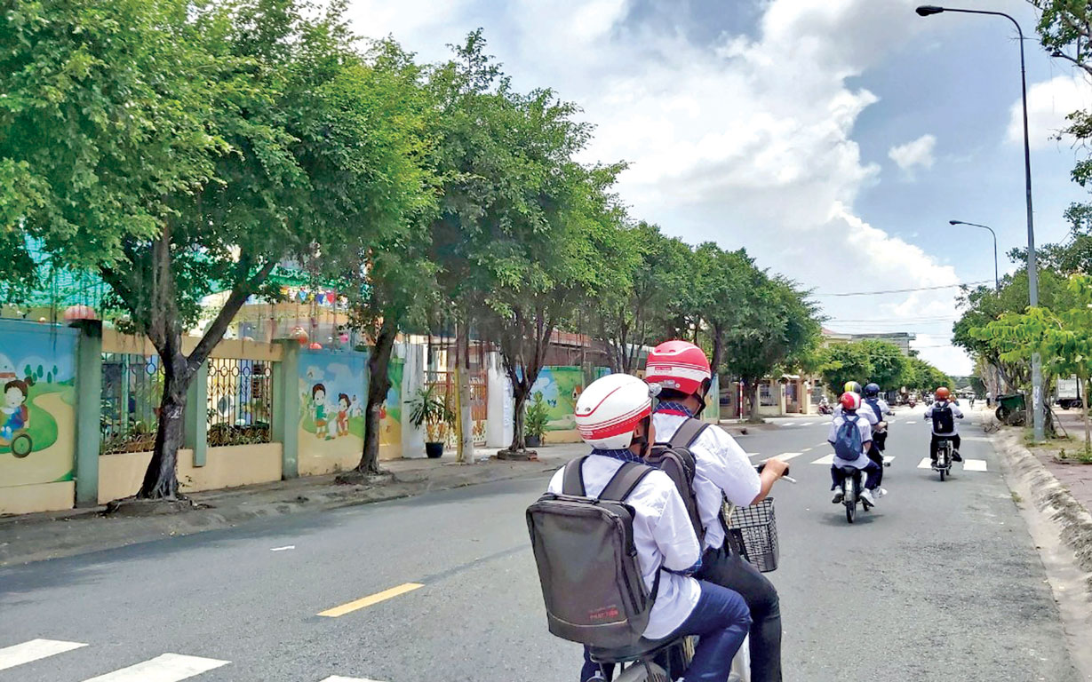 Học sinh chấp hành nghiêm việc đội nón bảo hiểm khi đi xe đạp điện (Ảnh tư liệu)