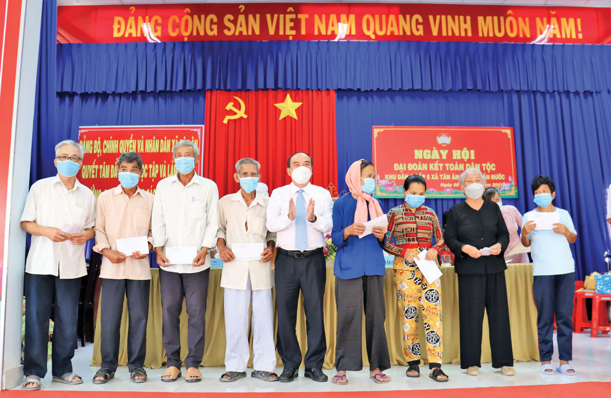 Chủ tịch UBMTTQ Việt Nam tỉnh - Trương Văn Nọ (đứng giữa) trao quà cho người nghèo ở xã Tân Ân, huyện Cần Đước (Ảnh: Cẩm Tú)