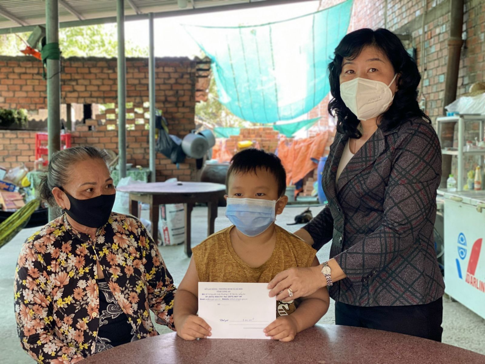 Giám đốc Sở Lao động - Thương binh và Xã hội - Nguyễn Hồng Mai (bìa phải) trao tiền hỗ trợ trẻ em mồ côi do Covid-19