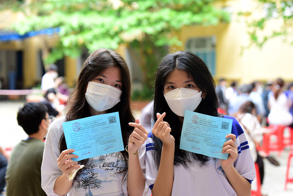 Hai em Thảo Nhi và Trúc Hân khoe giấy chứng nhận đã tiêm 2 mũi vắc xin ngừa COVID-19 - Ảnh: DUYÊN PHAN