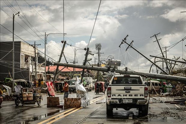 Philippines warned of health crisis due to Typhoon Rai Fallen electric pylons block a road while a sign asking for food (L), is displayed along a road in Surigao City, the Philippines. (Photo: AFP/VNA)