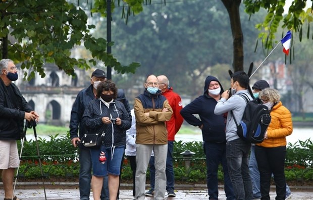 Vietnam to discontinue automatic stay extension for foreigners as int'l flights resume Foreign citizens visiting Hoan Kiem Lake in Hanoi in February 2021.(Photo: VNA)