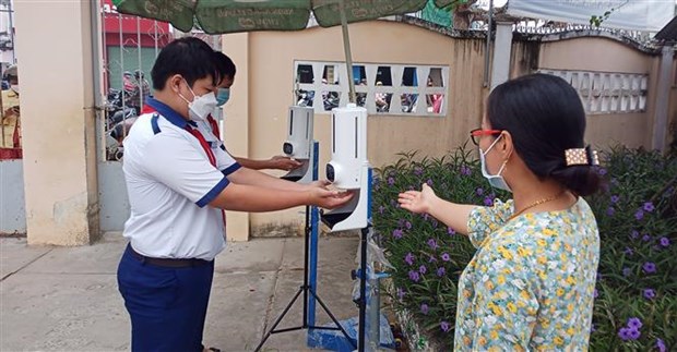 Students have their body temperature checked and use hand sanitiser before entering a school. (Photo: VNA)