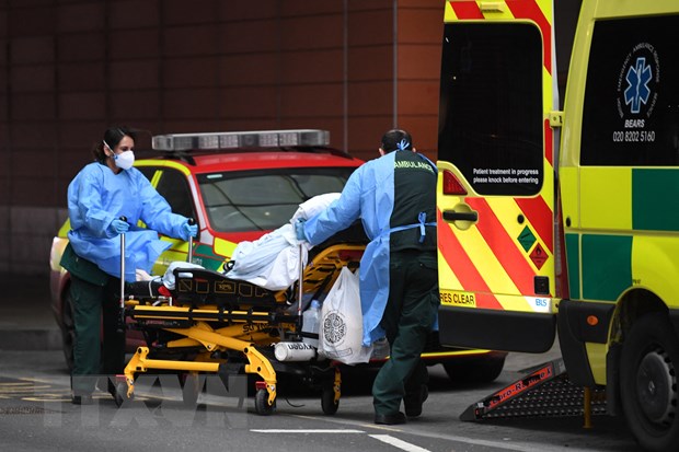 Nhân viên y tế chuyển bệnh nhân nhiễm COVID-19 tới bệnh viện ở London, Anh. (Ảnh: AFP/TTXVN)