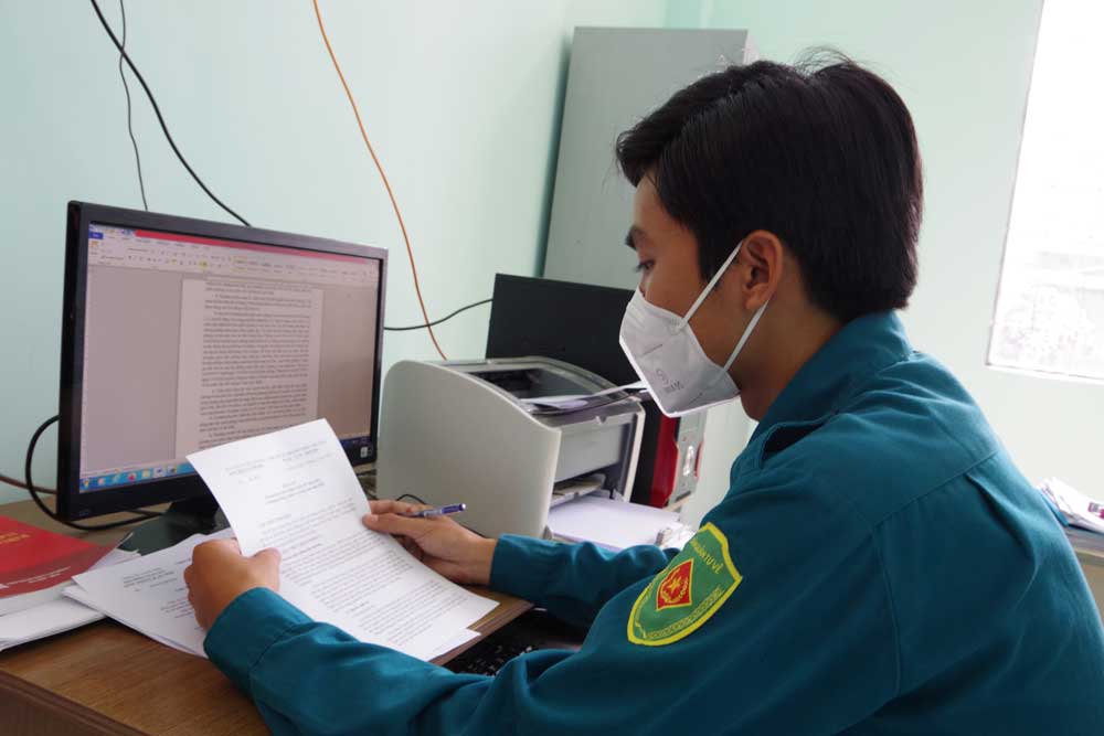 Dân quân Trần Trung Hiếu soạn thảo văn bản và chỉnh sửa báo cáo trên máy tính