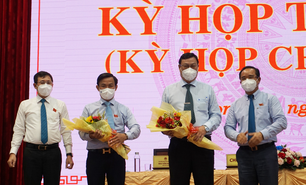 The chairman of the meeting gives flowers to Mr. Nguyen Minh Hung - former Director of the Department of Construction (2nd, L) and Mr. Nguyen Thanh Tiep - former Director of the Department of Education and Training