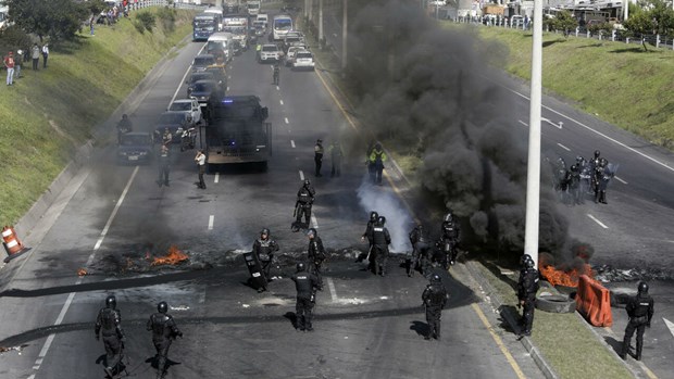 Cảnh sát chống bạo động giải tán một chốt chặn của người biểu tình tại cao tốc nối sân bay Quito. (Ảnh: AFP)