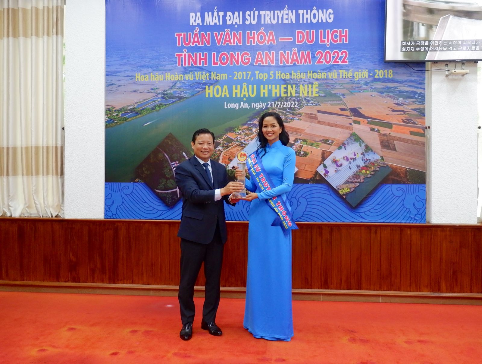 Vice Chairman of the Provincial People's Committee - Pham Tan Hoa presents the ribbon and logo of the title of Media Ambassador to Miss H'Hen Nie