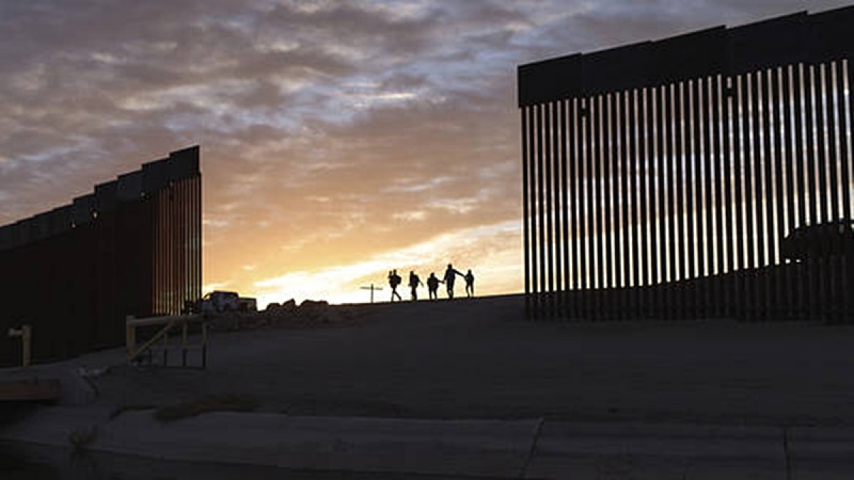 Người nhập cư đi qua lỗ hổng của tường biên giới Mỹ ở Yuma để vào lãnh thổ Mỹ. Ảnh: AP.