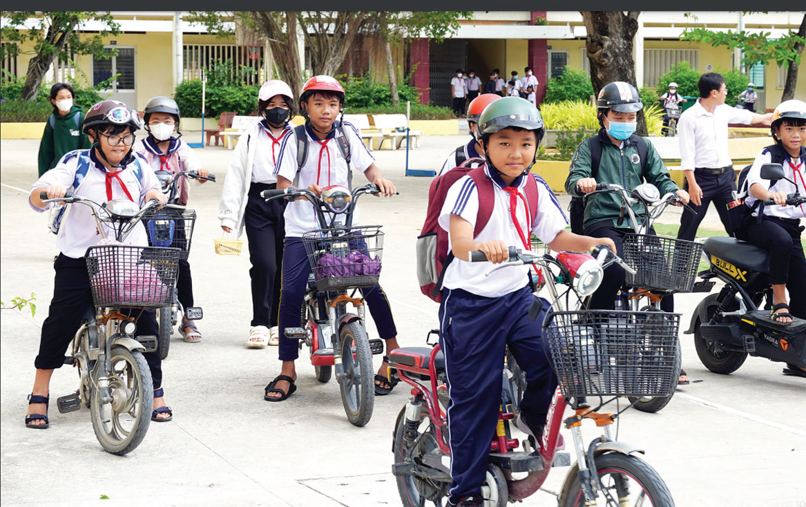 Học sinh đi xe đạp điện đội mũ bảo hiểm đúng quy định