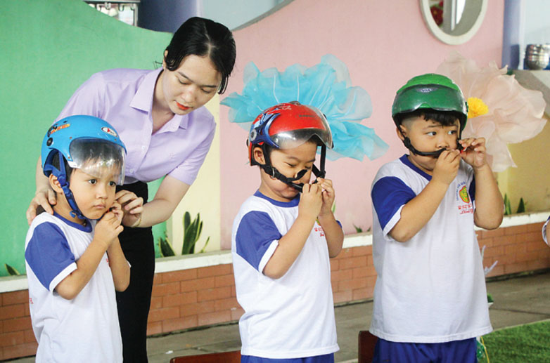 Ươm mầm ý thức Các bé lớp lá được cô hướng dẫn cách đội mũ bảo hiểm trong giờ hoạt động trải nghiệm tại trường
