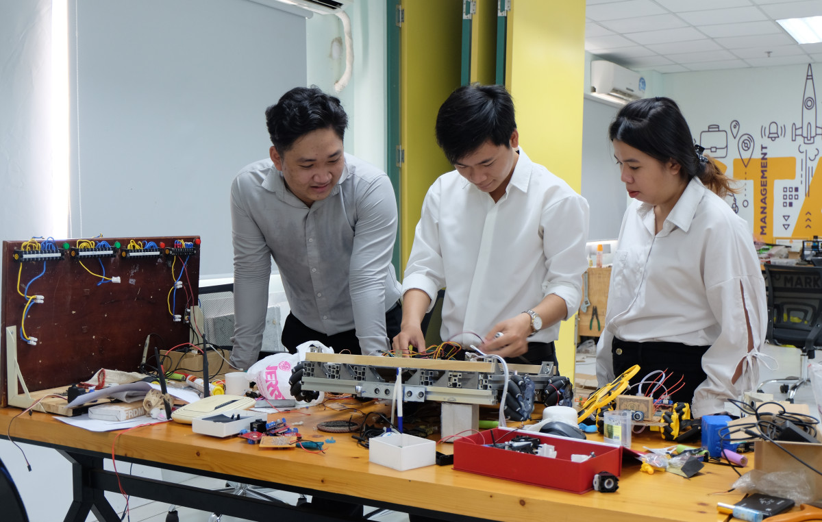Nguyễn Vạn Tín (giữa) và các bạn trong nhóm sinh viên Trường Đại học Kinh tế Công nghiệp Long An lắp ráp, chỉnh sửa mô hình robot chạy bàn trong nhà hàng
