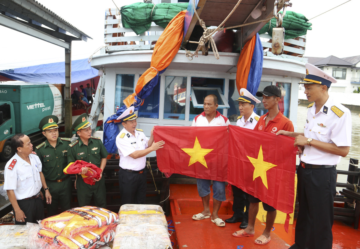 Cán bộ Vùng 2 Hải quân tặng cờ Tổ quốc cho ngư dân tại cảng cá Trần Đề, huyện Trần Đề, tỉnh Sóc Trăng
