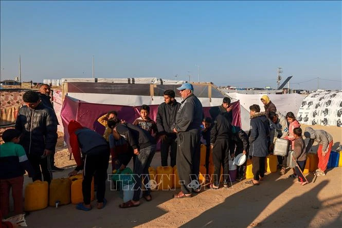 Người tị nạn Palestine xếp hàng lấy nước sinh hoạt tại khu lều tạm ở Dải Gaza ngày 16/1/2024. (Ảnh: AFP/TTXVN)